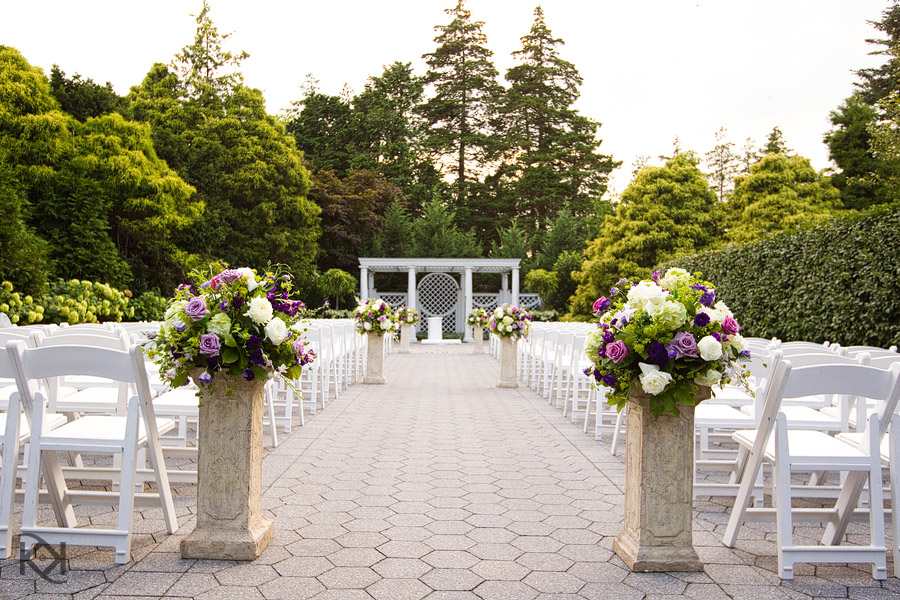 outdoor garden weddings- formal garden setting with white chairs, pillars for flowers, and and white wedding backdrop