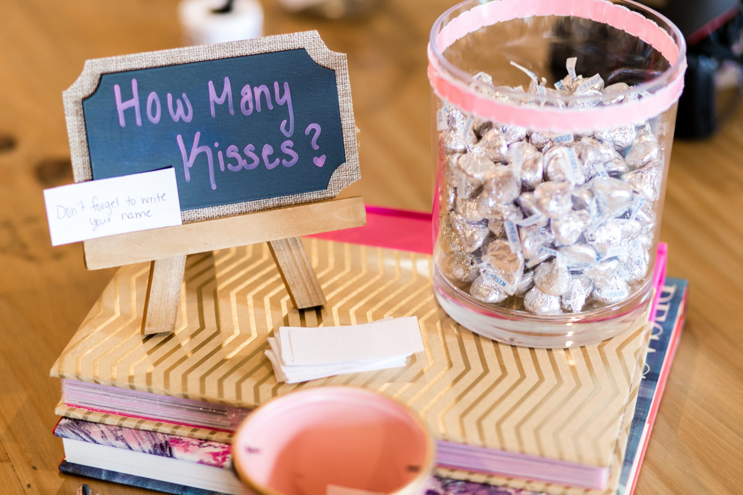Bridal Shower Ideas. A chalkboard sign reading how many kisses with a clear glass vase full of hershey kisses. Bridal shower games.